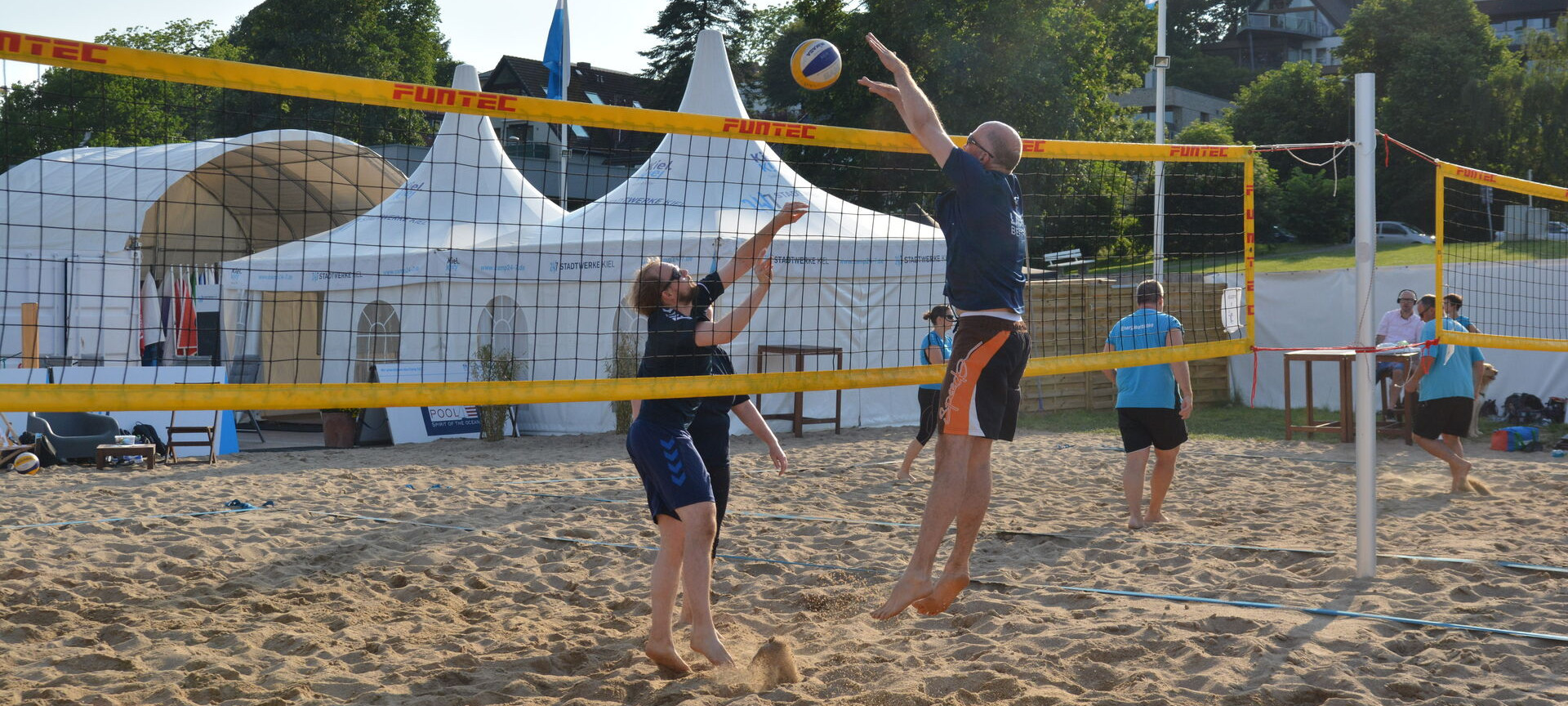 Zwei Teams spielen Beachvolleyball im Segelcamp