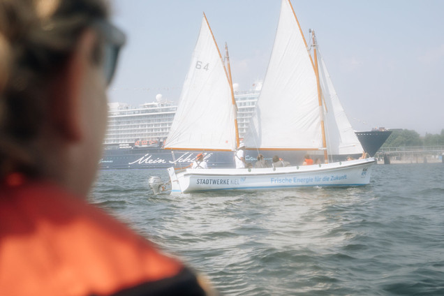 Frau guckt auf Segelboot an der Förde