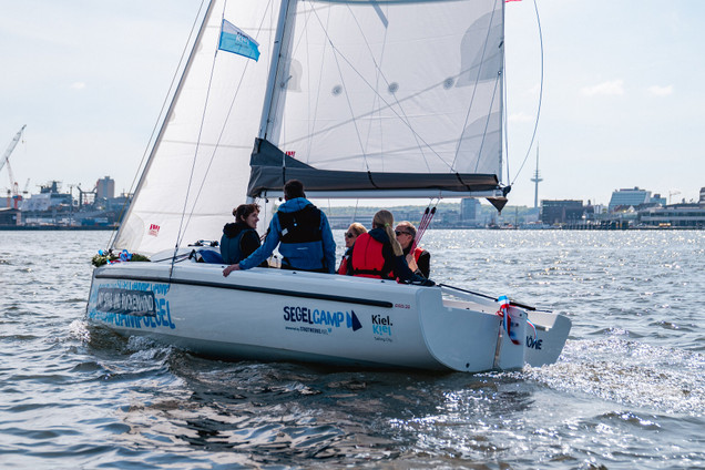 Vier junge Menschen und einem Segeltrainer auf der Aira 22 in einem Kurs vom Segelcamp Kiel