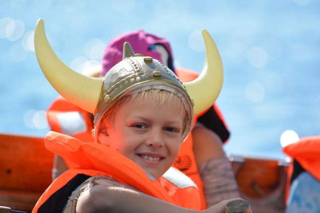 Lächelnder Junge mit Vikinger-Helm auf Kutter bei Geburtstagsfeier