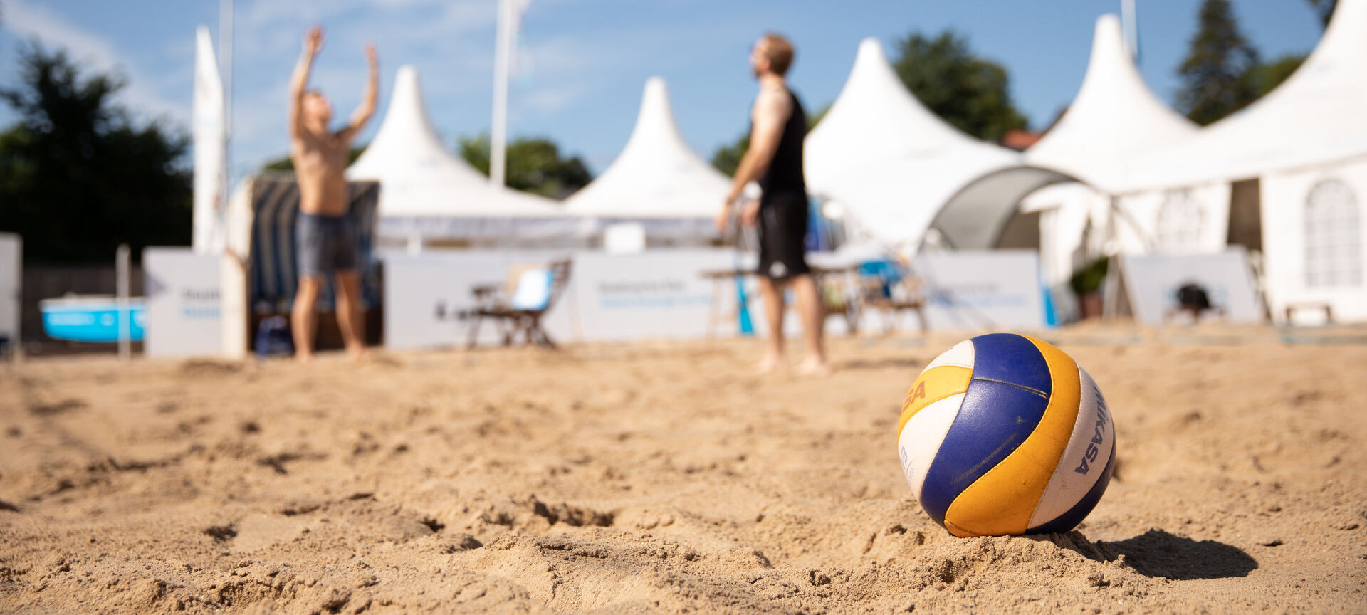 Zwei junge Männer spielen Beachvolleyball im Segelcamp, der Volleyball steht im Vordergrund