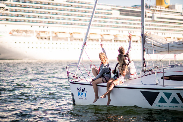 Gruppe auf Segelboot mit Blick auf Kreuzfahrtschiff