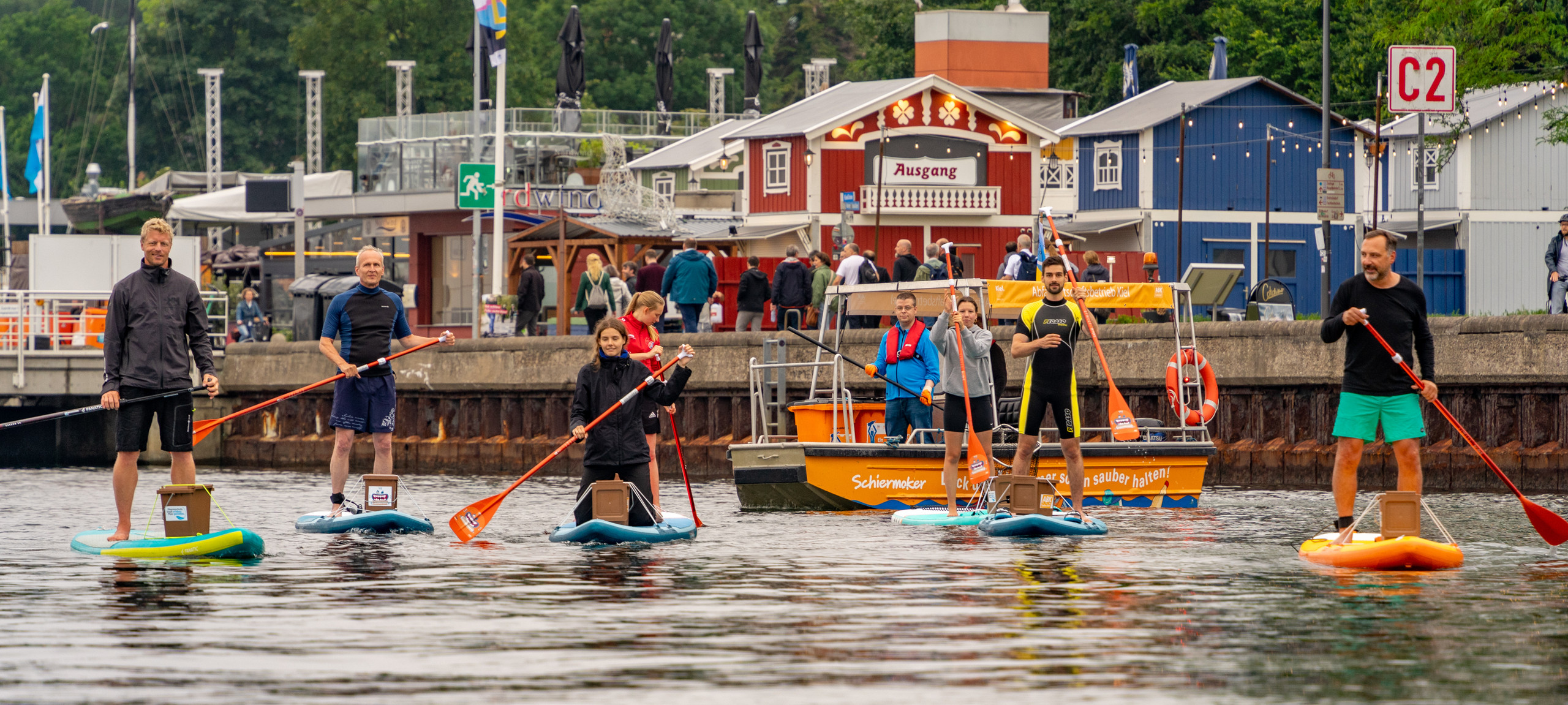 Viele Menschen sammeln Müll aus dem Meer auf SUP Boards